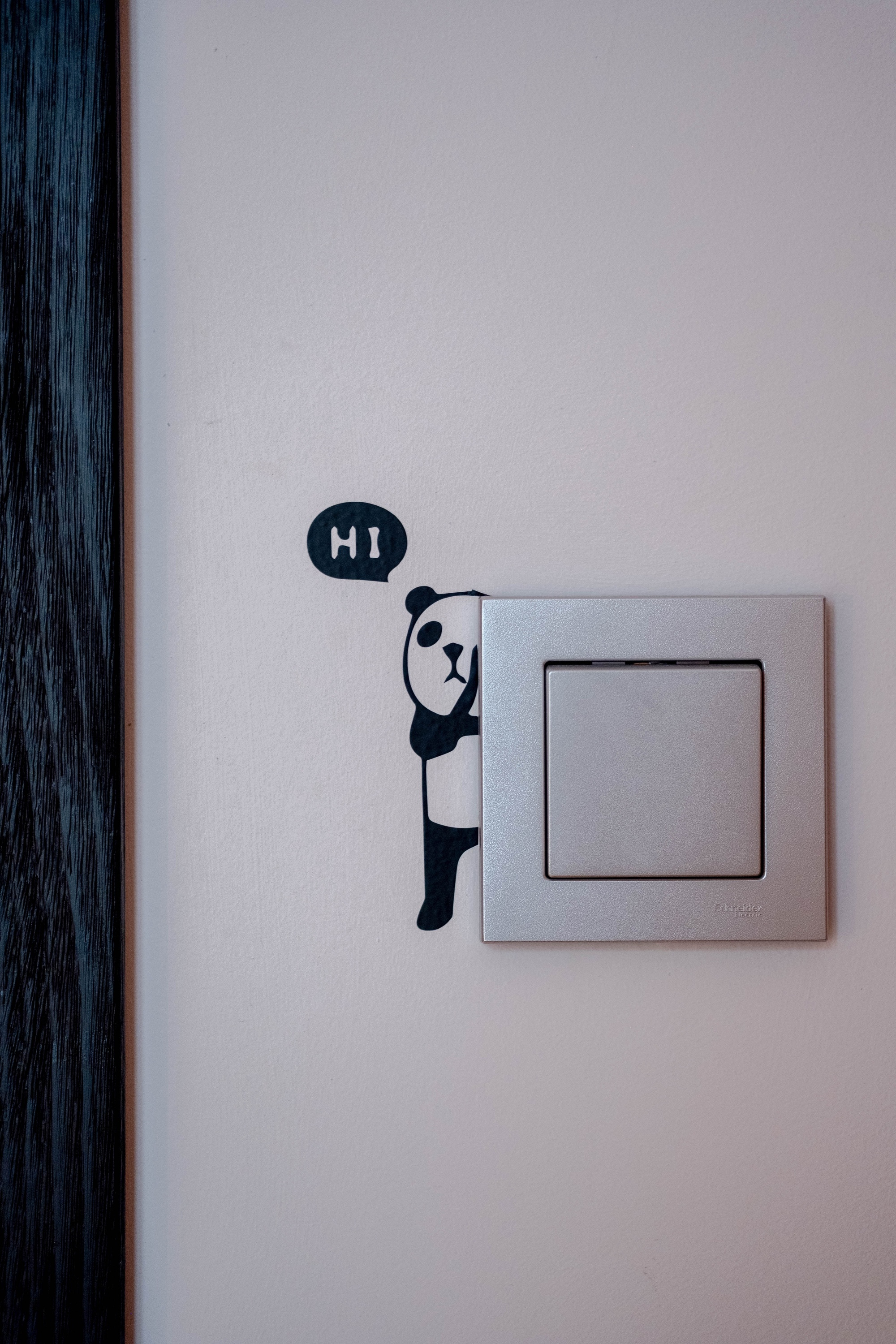 a light switch with a sticker of a panda saying hi