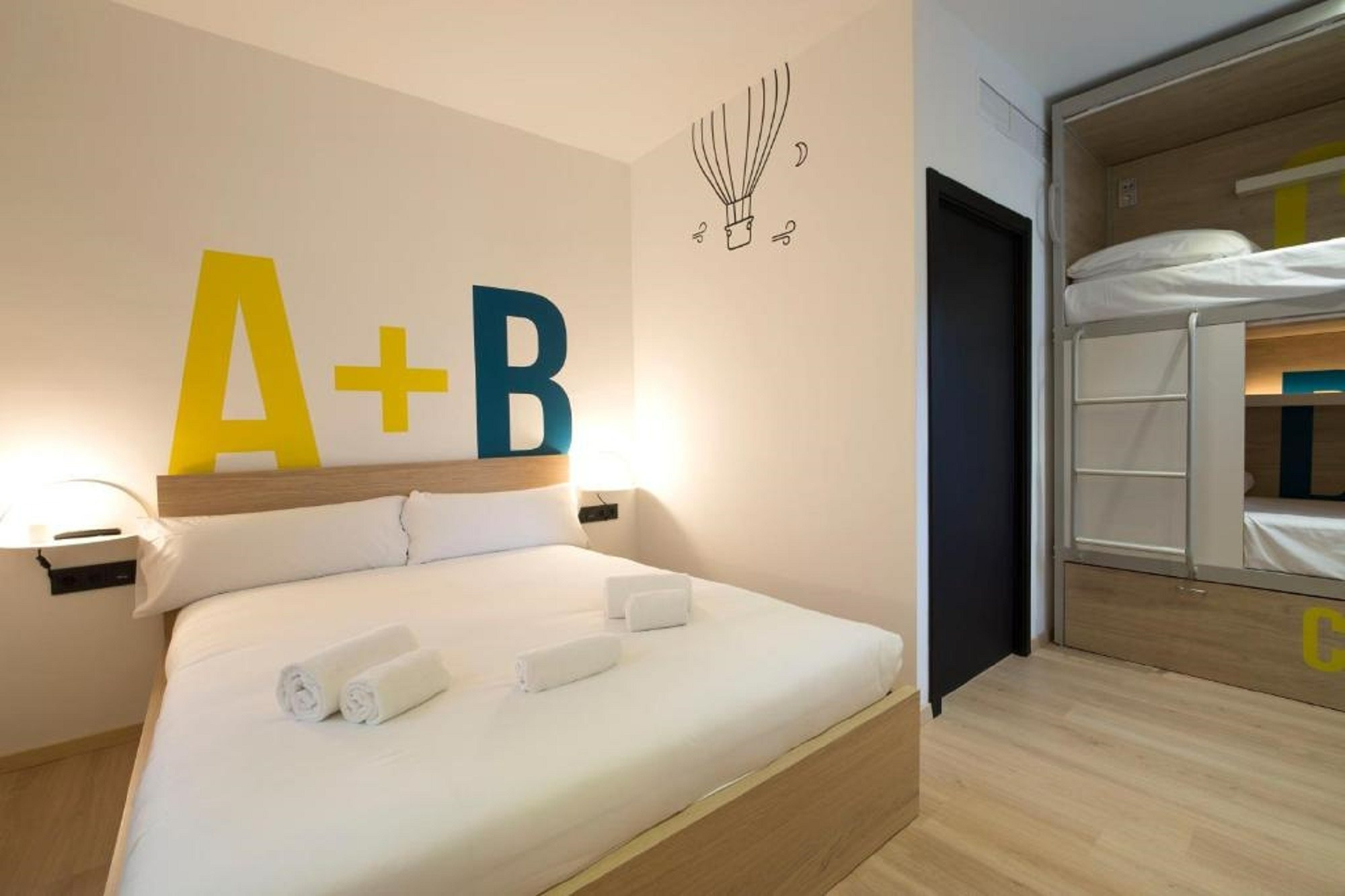 una habitación con una cama y una litera con las letras a + b pintadas en la pared