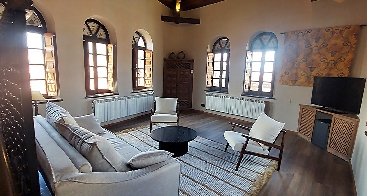 Salón acogedor en Palacio Vald­er­rab­a­nos con sofá, sillones y TV.