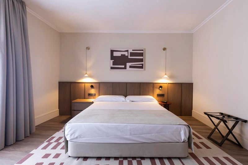 Habitación de hotel moderna con cama doble, mesitas de noche, lámparas y Hotel Palacio Valderrabanos.