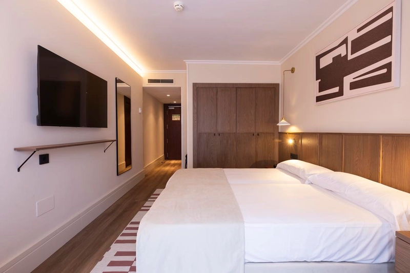 Habitación doble con dos camas, TV, espejo y armario de madera. Hotel Palacio Valderrabanos