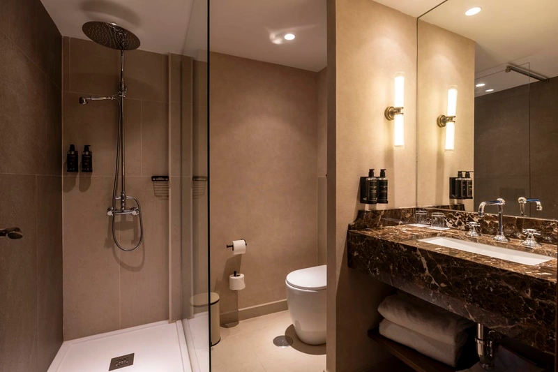 Baño moderno con ducha, inodoro y tocador con mármol. Hotel Palacio Valderrabanos