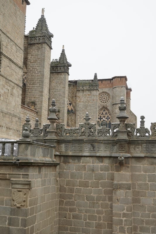 Una imponente edificación de piedra de estilo gótico, adornada con intrincados pináculos y rosetones y con leves trazas de nieve, se eleva bajo un cielo claro.