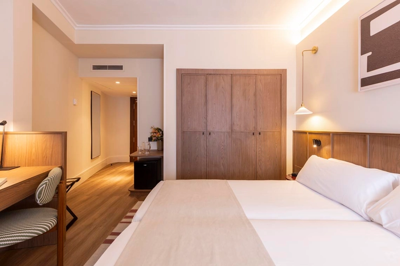 Habitación moderna de hotel con cama doble, armario de madera y escritorio. Hotel Palacio Valderrabanos