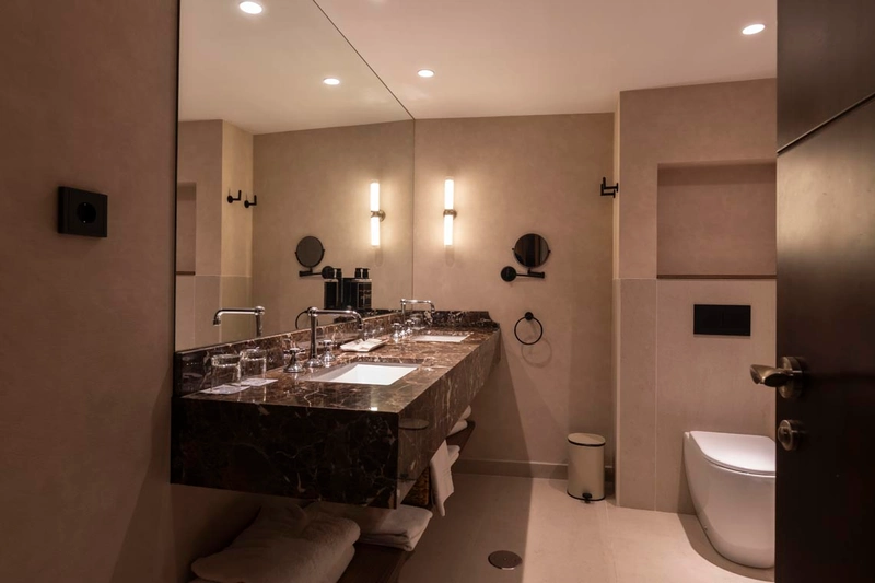 Baño elegante con doble lavabo de mármol y artículos de tocador, ideal para un Hotel Palacio Valderrabanos de lujo.