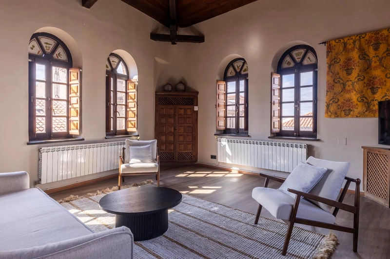 Hotel Palacio Valderrabanos: Amplia sala con ventanas arqueadas, mueble de madera y sillones cómodos.