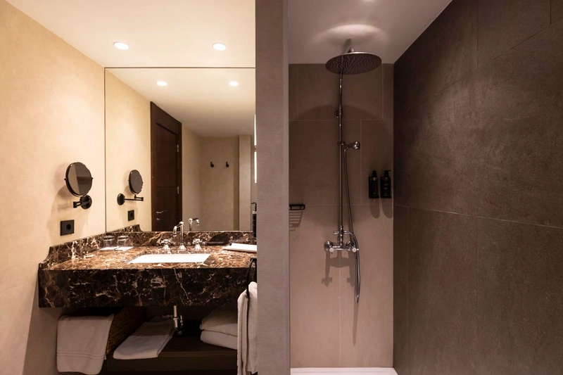 Elegante baño de hotel con ducha y lavabo de mármol. Hotel Palacio Valderrabanos