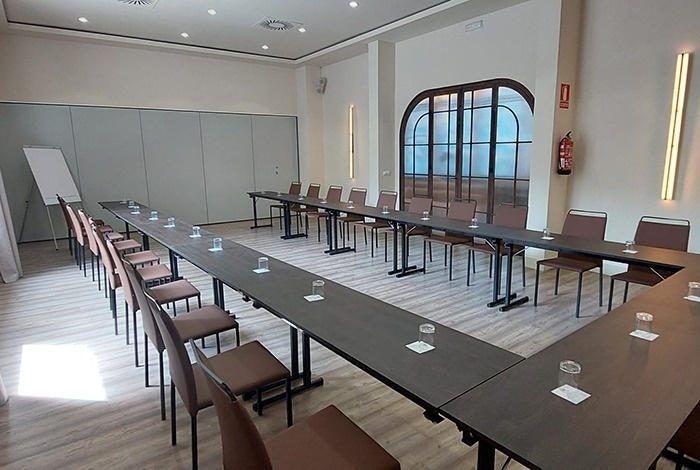 una sala de conferencias con mesas y sillas en forma de u
