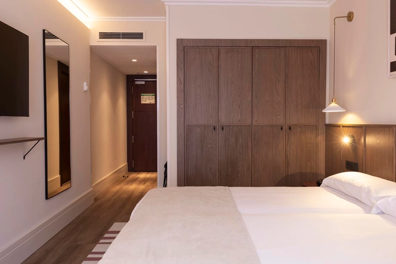 Habitación con armario de madera, cama cómoda yHotel Palacio Valderrabanos.
