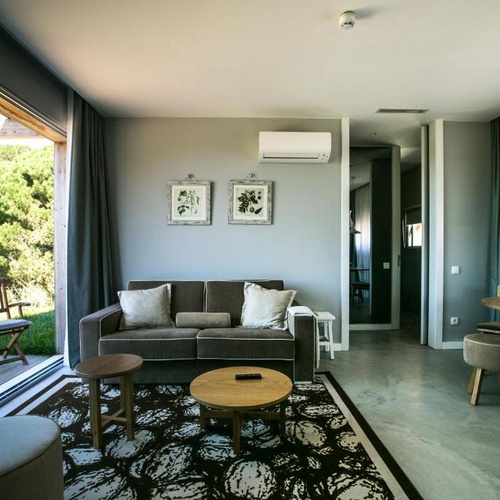 Sala de estar moderna no Vale d'Azenha com sofá, mesa e vista para a natureza.