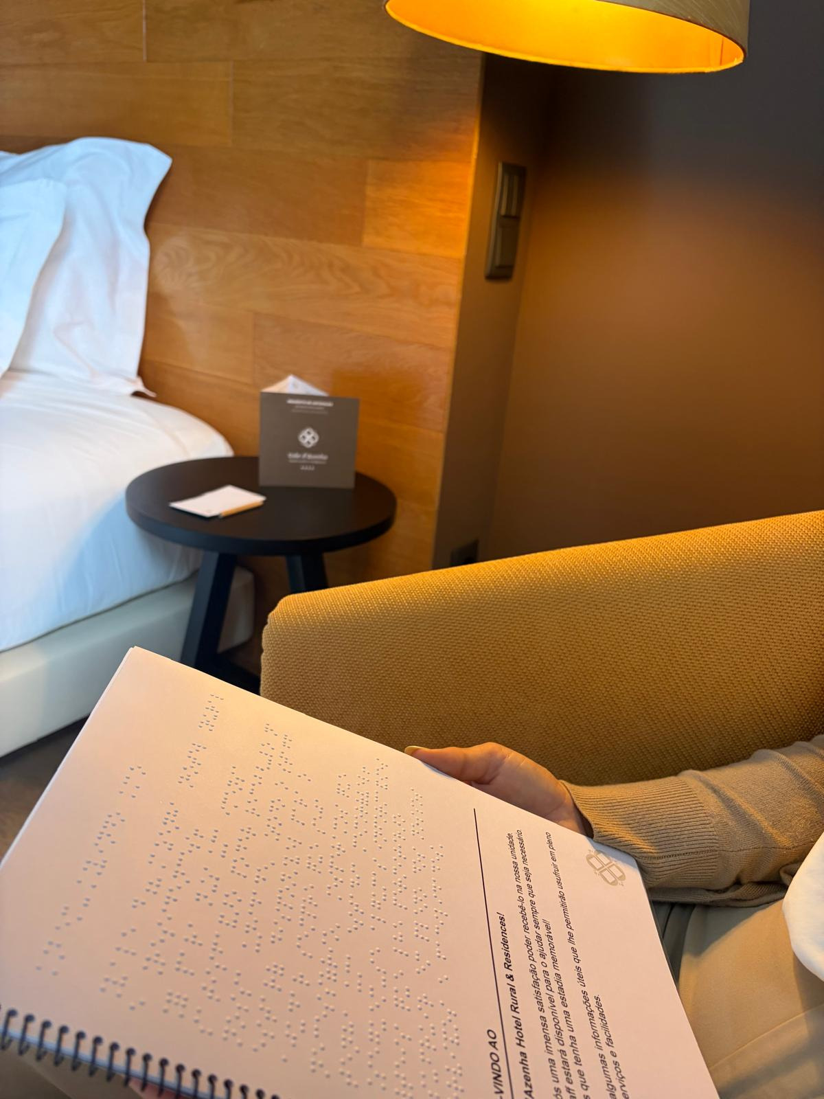 Braille guide open in the room, with the bed and side table in the background.