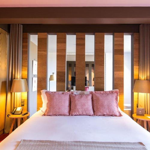 Cama de luxo no Vale d Azenha com detalhes em madeira e iluminação aconchegante.