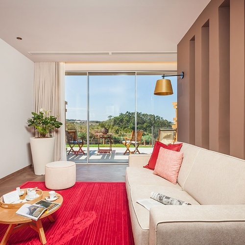 Sala de estar do Vale d'Azenha com sofá bege e vista para o exterior.