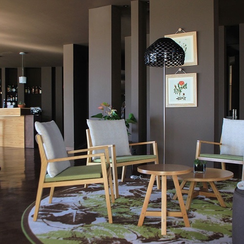 Lounge moderno no Vale d'Azenha com poltronas de madeira e tapete botânico.