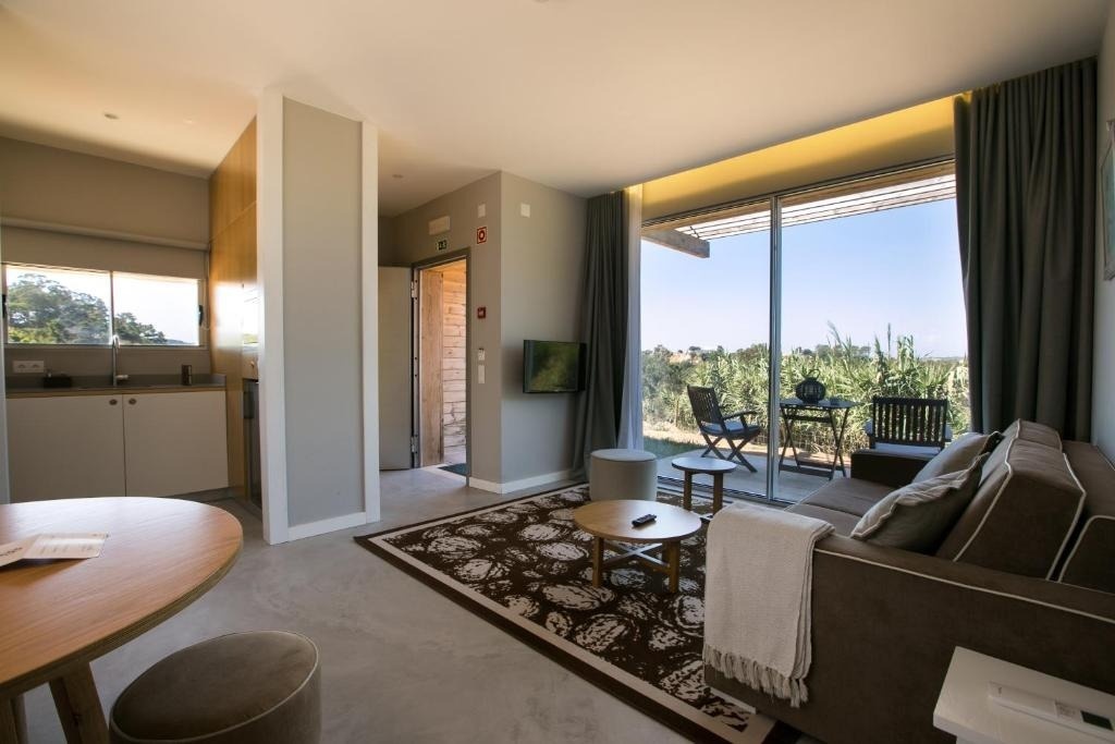 Este moderno salón-comedor con cocina integrada se abre a una terraza exterior que ofrece vistas a la vegetación.