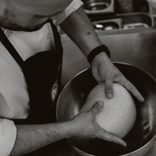 Chef no Vale d'Azenha a amassar massa numa taça de aço inox.