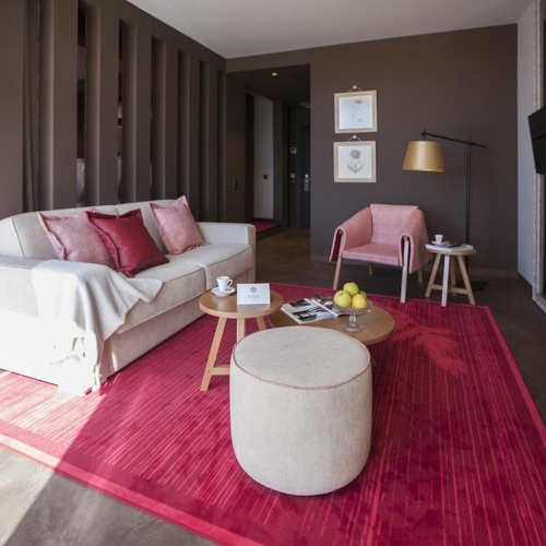 Sala de estar de Vale d'Azenha: sofá, poltrona cor de rosa e tapete vibrante.
