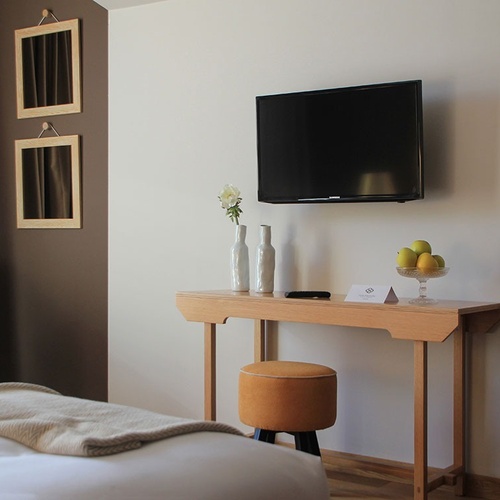 Quarto luxuoso no Vale d'Azenha com TV, espelho e poltrona confortável.