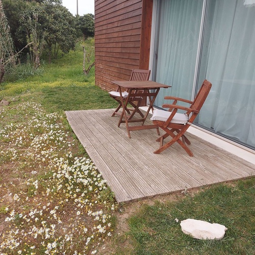 Terraço de madeira com mesa e cadeiras em Vale d Azenha, rodeado por natureza.
