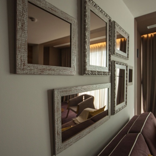 Reflexos elegantes no Vale d Azenha: espelhos decorativos sobre um sofá.