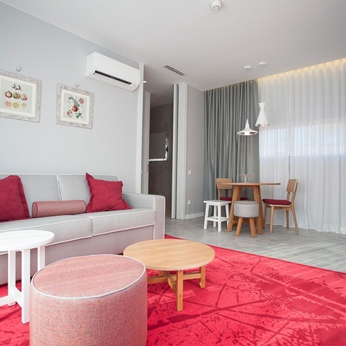Sala de estar de Vale d Azenha com sofá moderno, almofadas vermelhas e tapete colorido.