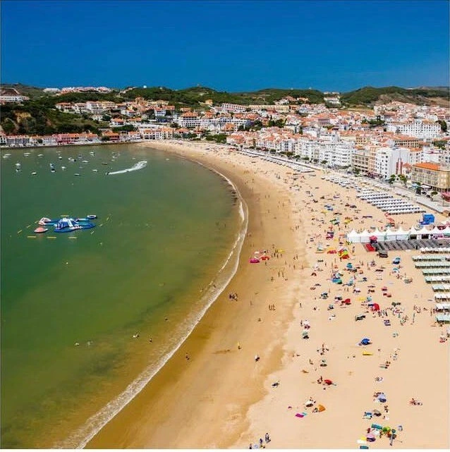 Aerial view of São Martinho do Porto bay, with its shell-shaped beach and the town around it.