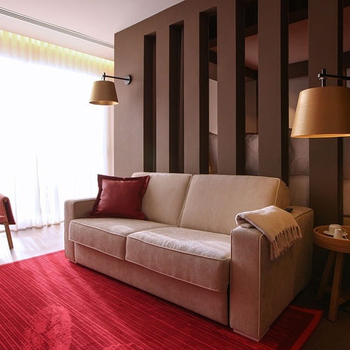 Sala elegante em Vale d'Azenha com sofá, poltrona rosa e tapete vermelho.
