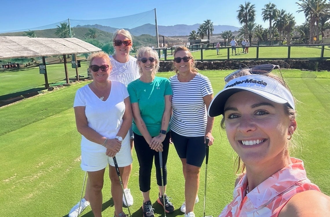 un grupo de mujeres posando para una foto en un campo de golf