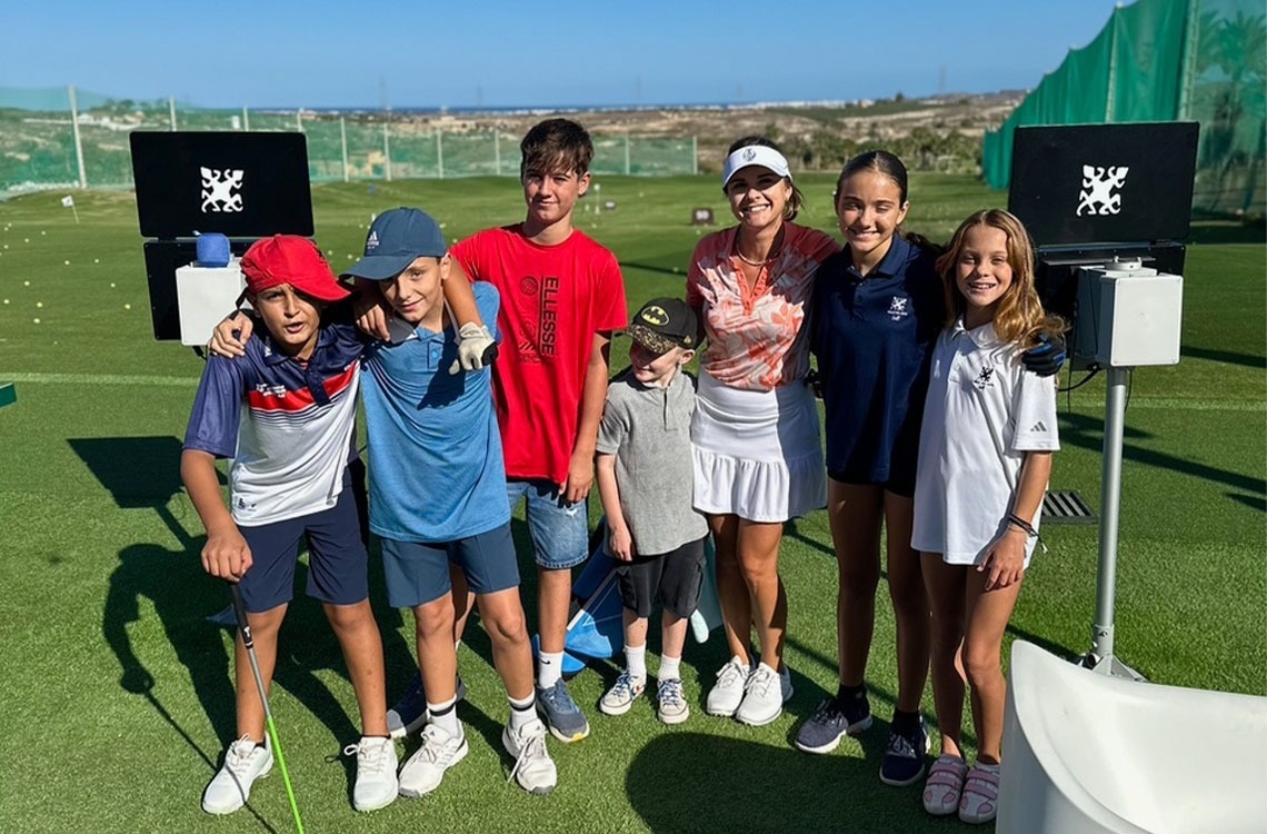 un grupo de niños posando para una foto en un campo de golf