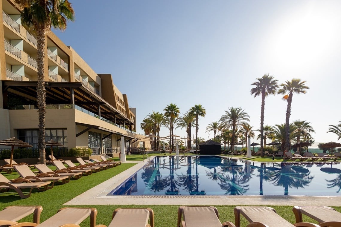 a large swimming pool surrounded by chairs and palm trees