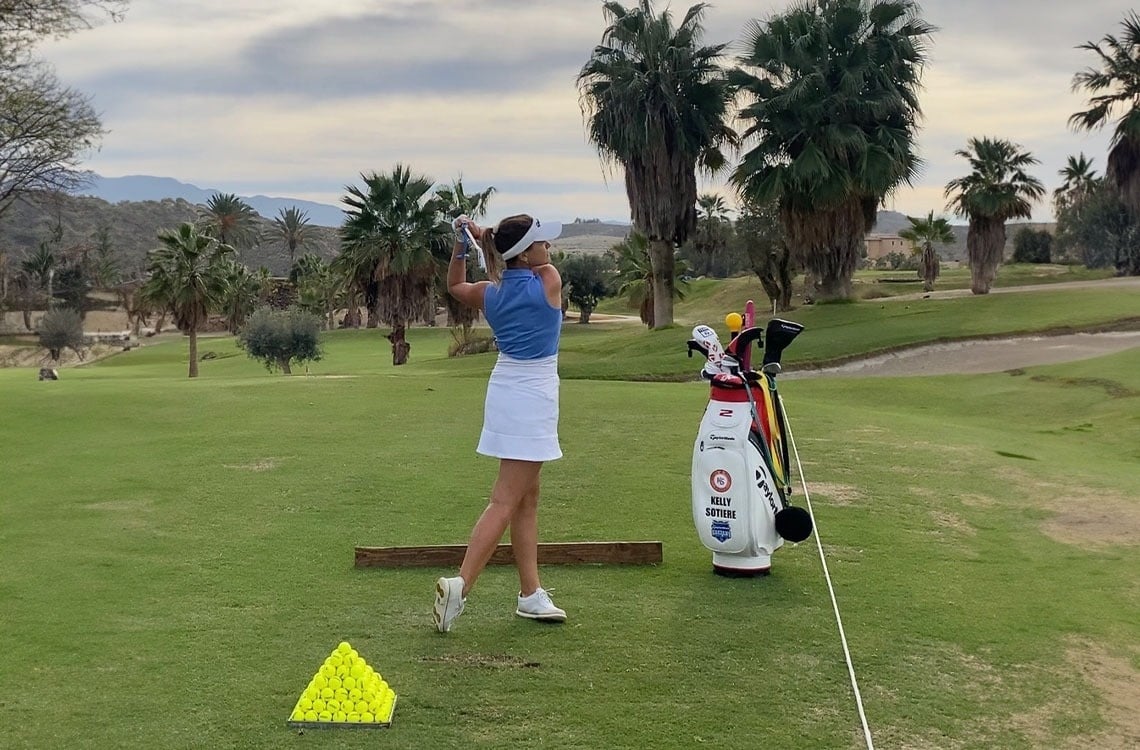 a woman swings a golf club on a golf course with a bag that says kelly brooks