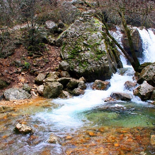 a waterfall is surrounded by rocks and trees