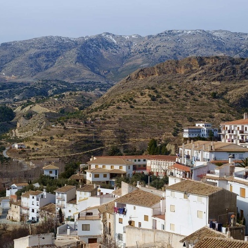 eine kleine Stadt liegt auf einem Hügel mit Bergen im Hintergrund