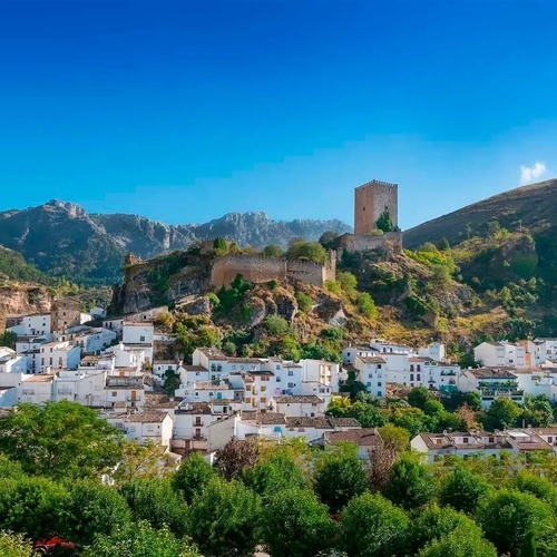 eine kleine weiße Stadt mit einem Schloss auf einem Hügel im Hintergrund
