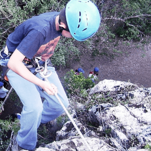 a man wearing a blue helmet is climbing a rock
