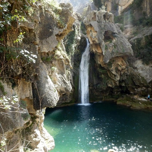 a waterfall is surrounded by rocks and a body of water