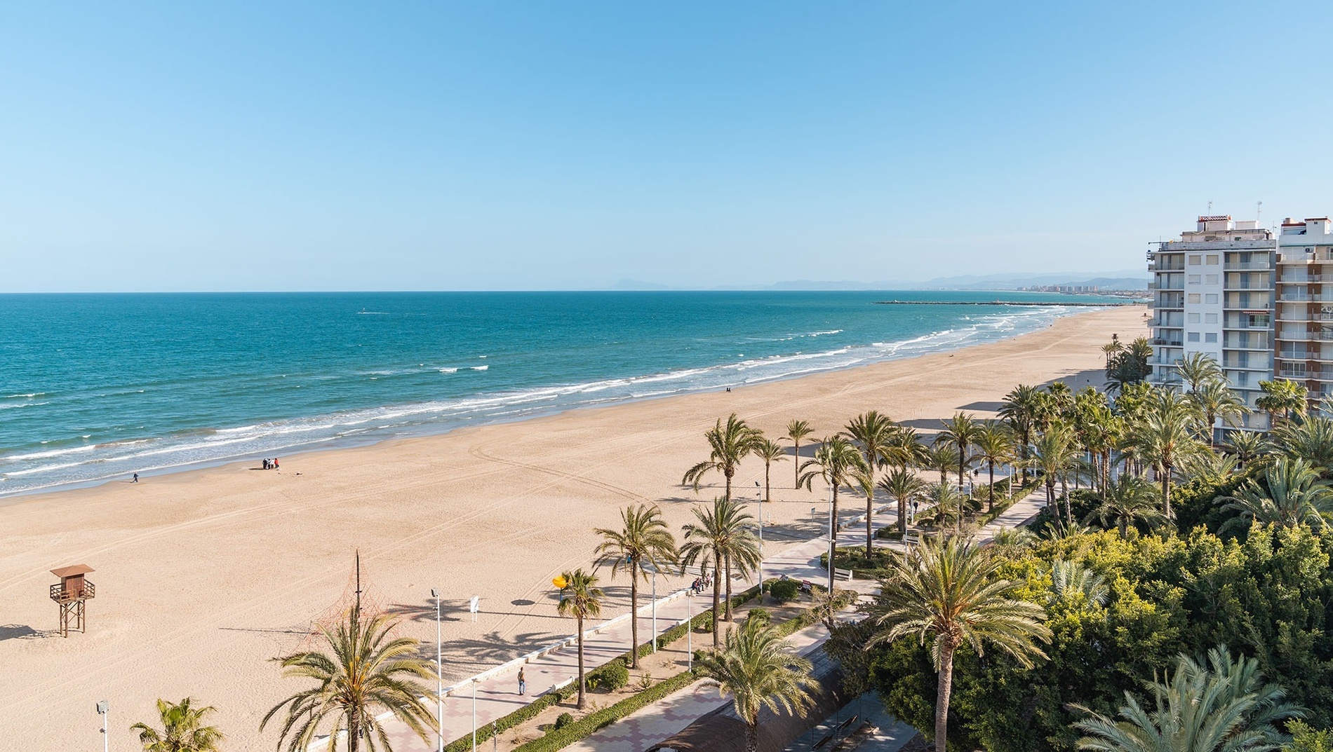 tres mujeres se paran en la playa con los brazos extendidos