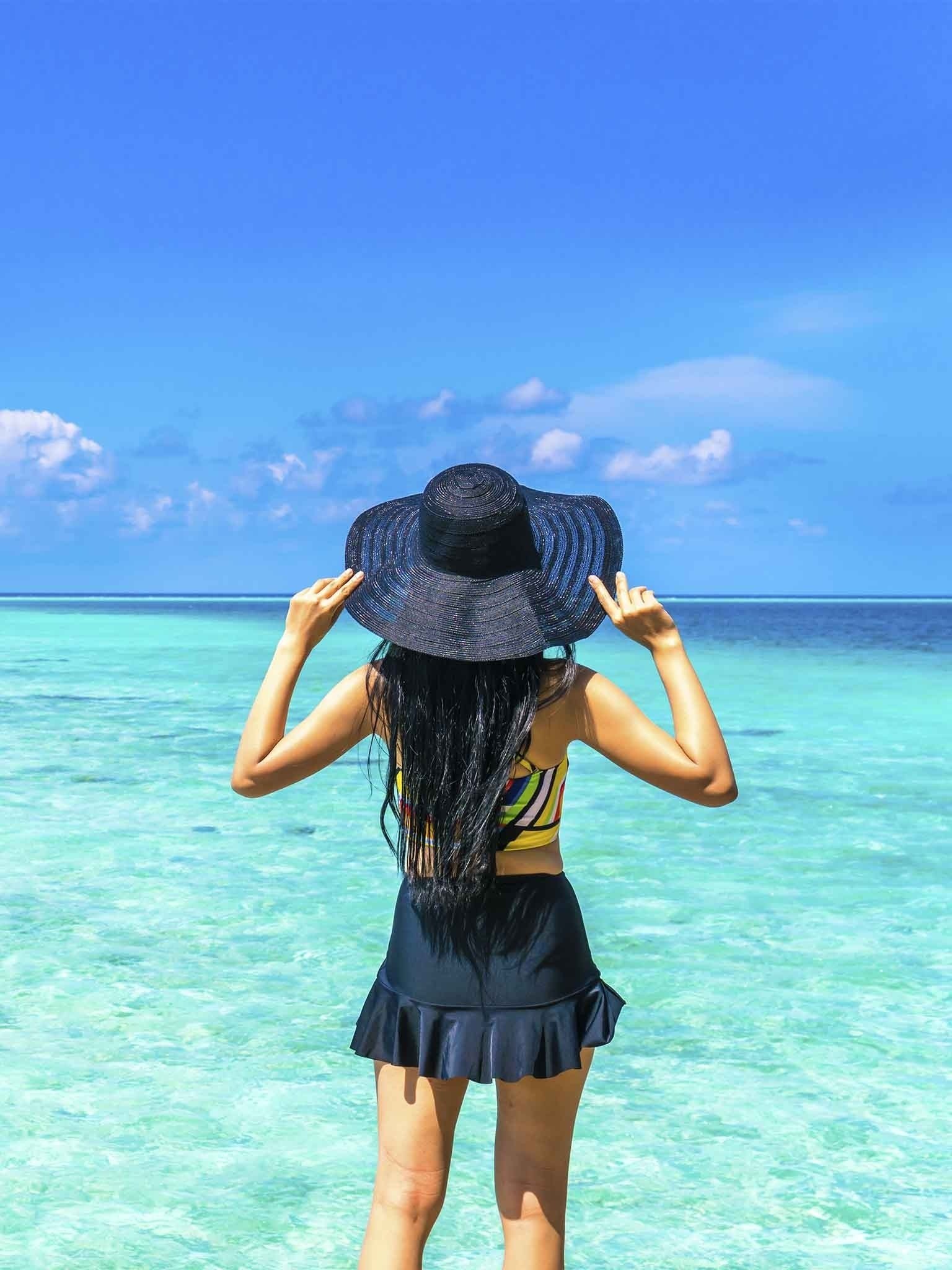 a woman in a red swimsuit is holding a man 's hand in the ocean