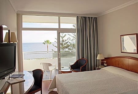 Spacious suite at VIK Hotel San Antonio featuring a cozy bed and sitting area.