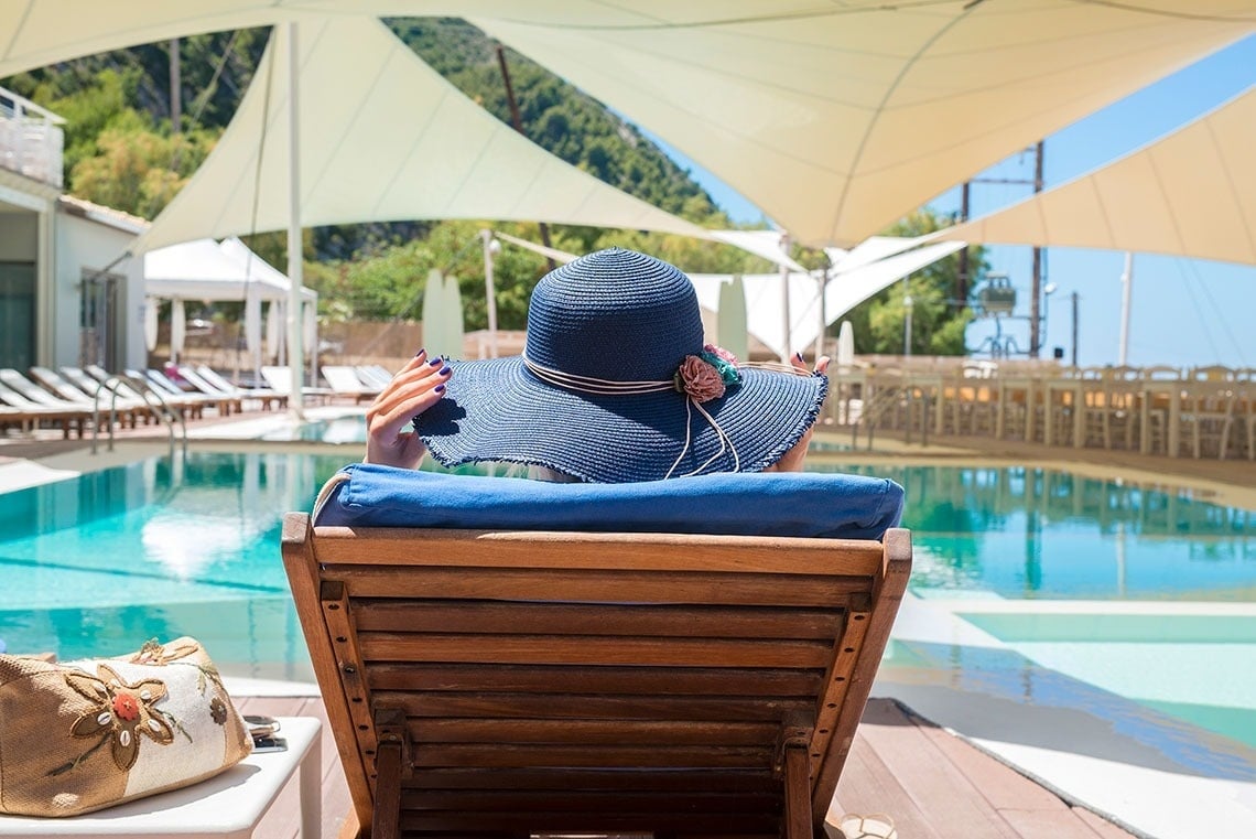 un tazón blanco lleno de cerezas rojas frente a una piscina