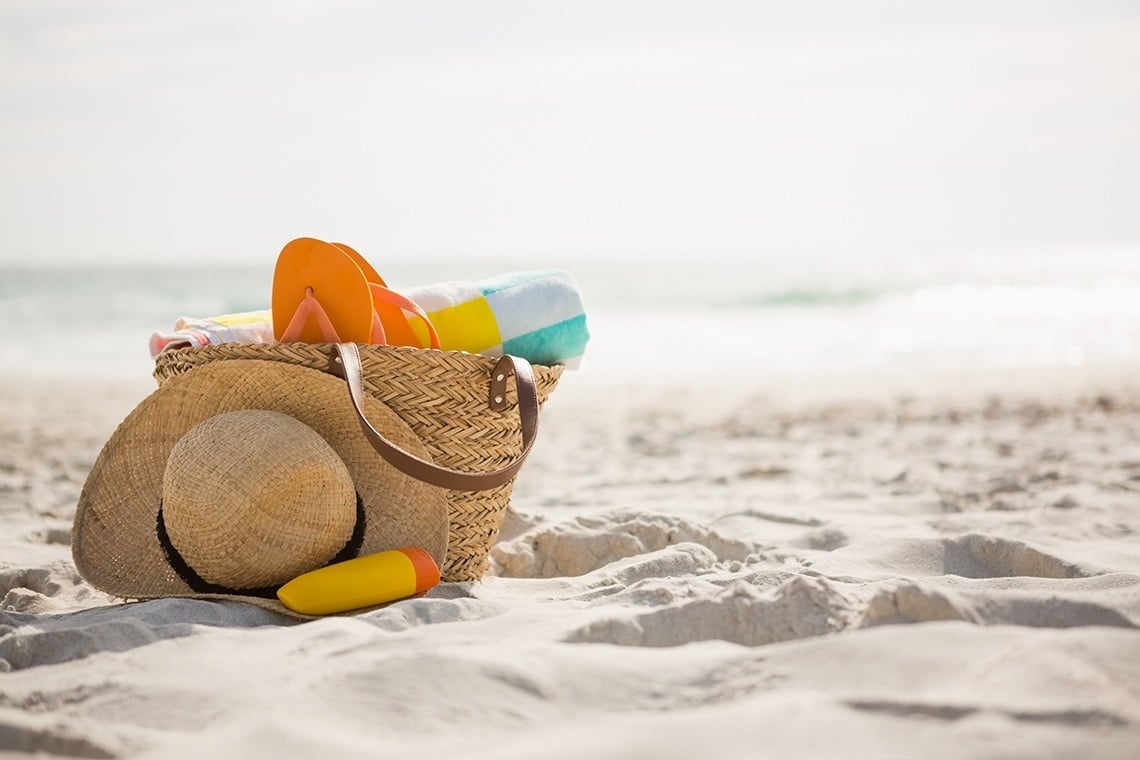 una canasta en la playa con un sombrero y una toalla