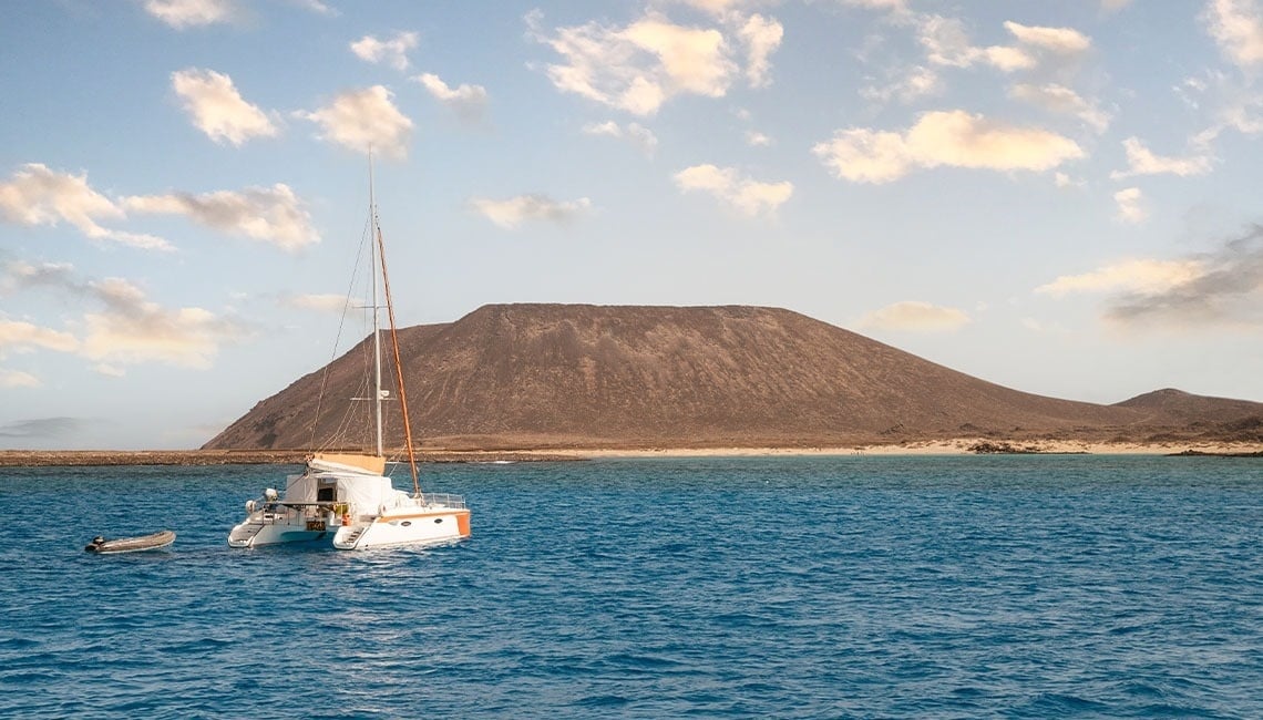un barco está anclado en el océano con una montaña en el fondo