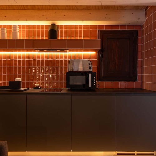 Modern kitchen in Apartamentos Vilafames Antic Palau with terracotta tiles and warm lighting.