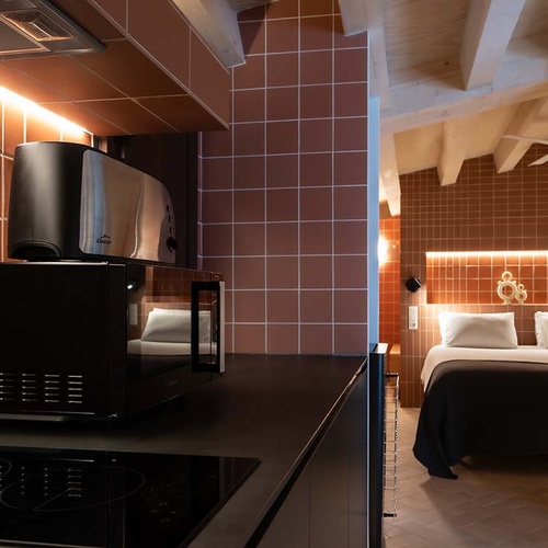 Apartamentos Vilafames: double bed in room with orange tiles and kitchenette.