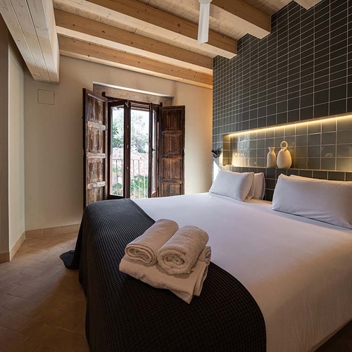Cozy bedroom in Apartamentos Vilafames Antic Palau, featuring a comfortable bed and rustic details.