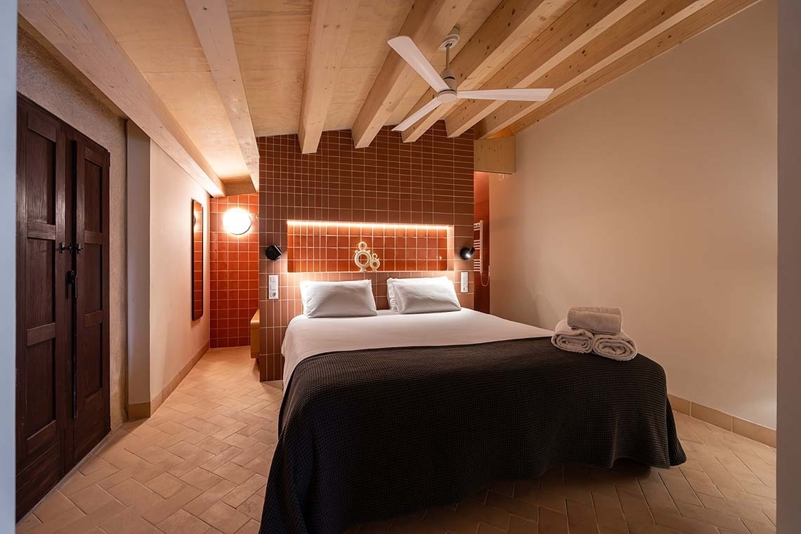 Habitación doble moderna en Apartamentos Vilafames Antic Palau con paredes de azulejo y techo de vigas.