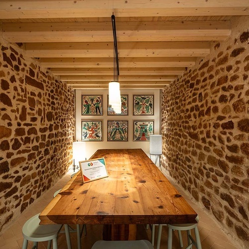 Rustic dining room with wooden table and paintings at Apartamentos Vilafames Antic Palau.