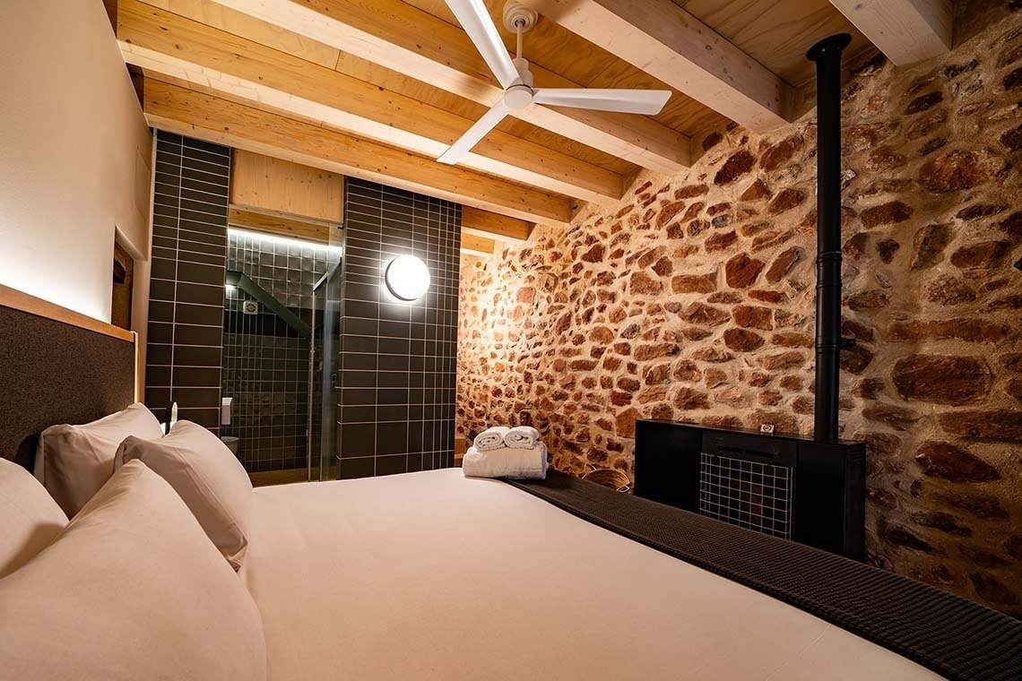 Acogedora habitación de lujo en Apartamentos Vilafames Antic Palau con chimenea y paredes de piedra.