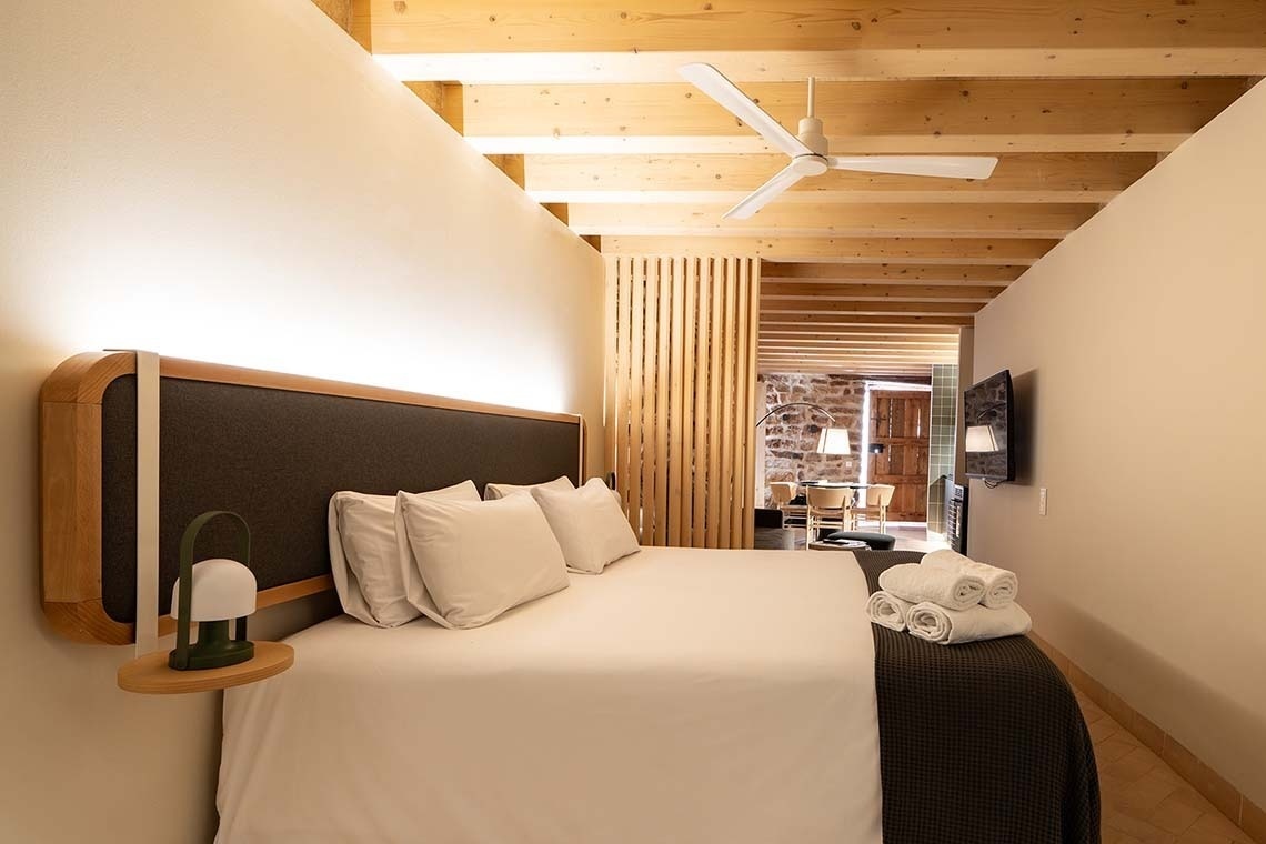 Habitación en Apartamentos Vilafames Antic Palau: cama cómoda, diseño moderno, vigas de madera.
