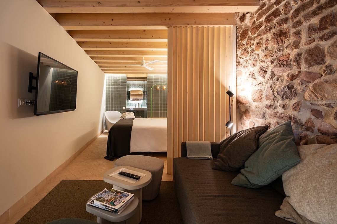 Suite con cama, TV y sofá en Apartamentos Vilafames Antic Palau.